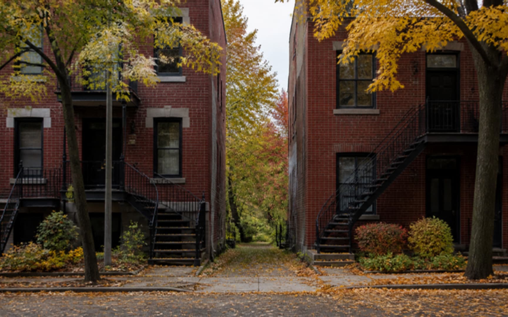 Rue montréalaise d'automne bordée de plex en brique avec escaliers extérieurs en fer forgé et ruelle feuillue — illustration générée par IA