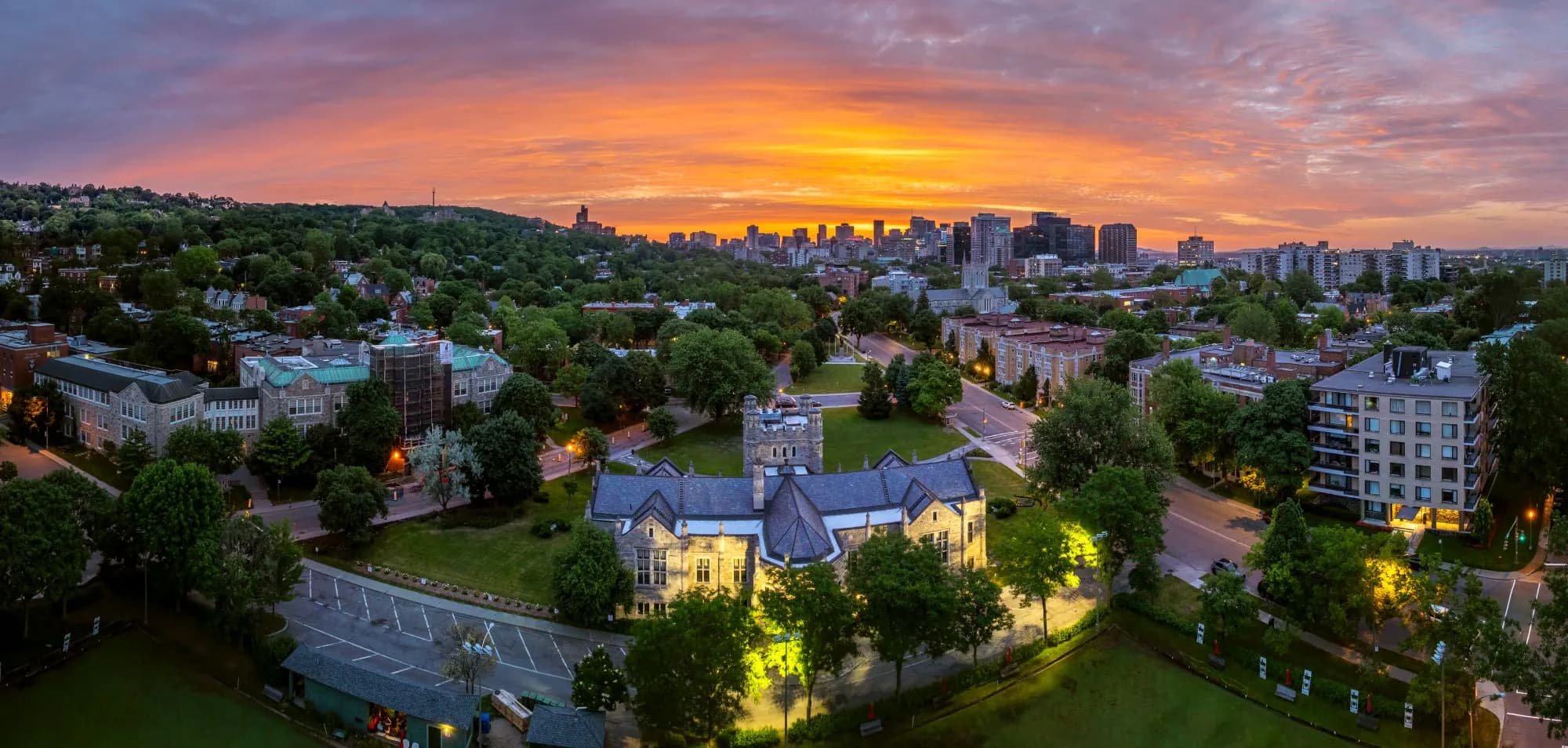 Vue aérienne de Westmount sous un ciel orangé, avec ses rues arborées et le centre-ville de Montréal à l'horizon